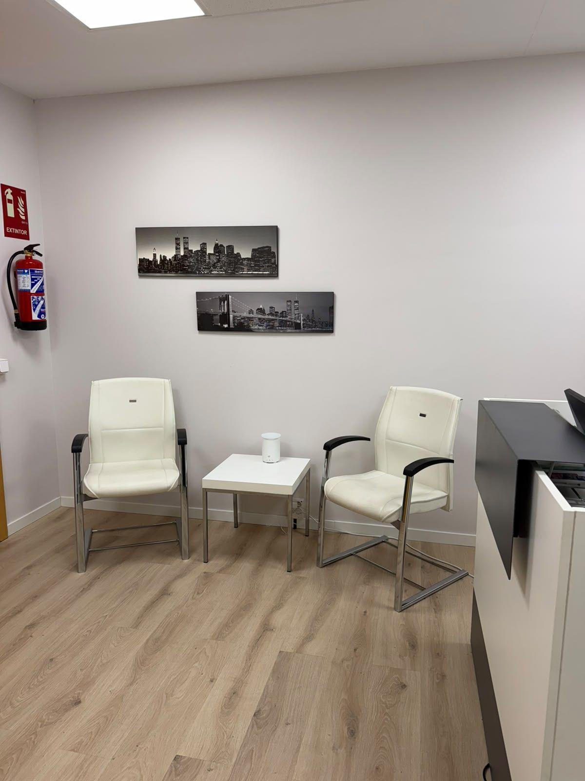 Zona de espera de la recepción con sillones blancos